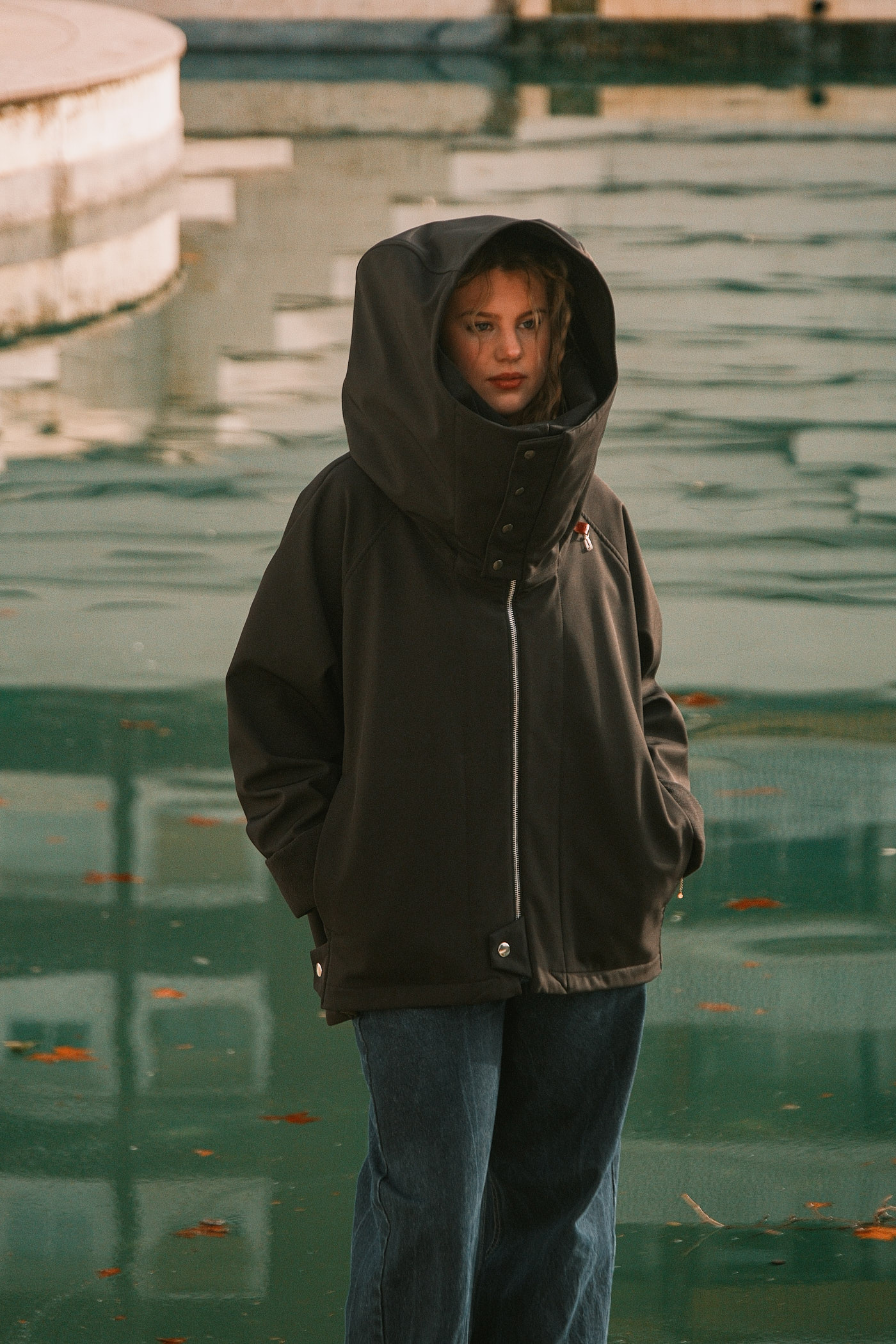 Chaqueta negra oversize unisex con capucha amplia y cuello escultural en escaleras de exterior